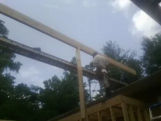 Carpenter setting a ridge beam over a new addition frame — Ice Dam Removal by Roofing Brothers in East Weymouth