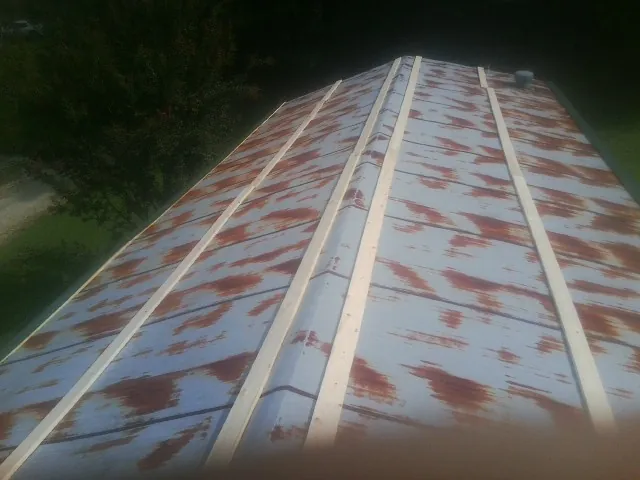 Rusted metal roof panels with new wood purlins before replacement in East Weymouth