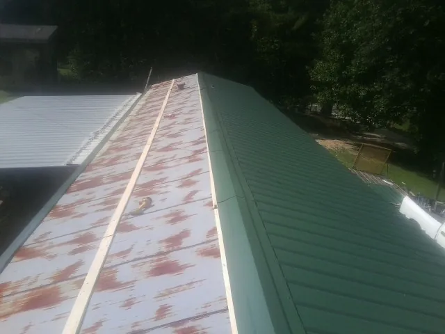 Old rusted panels beside newly installed green metal roofing — Wind Damage Roof Repair by Roofing Brothers in East Weymouth