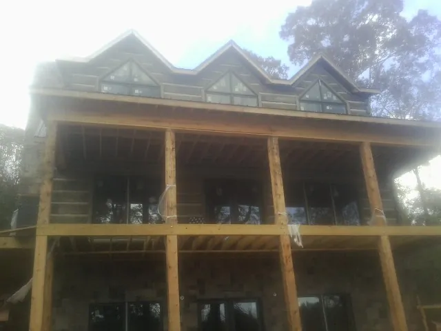 Dormers and porch framing on a large log home under construction — Roof Coating work by our crew in East Weymouth