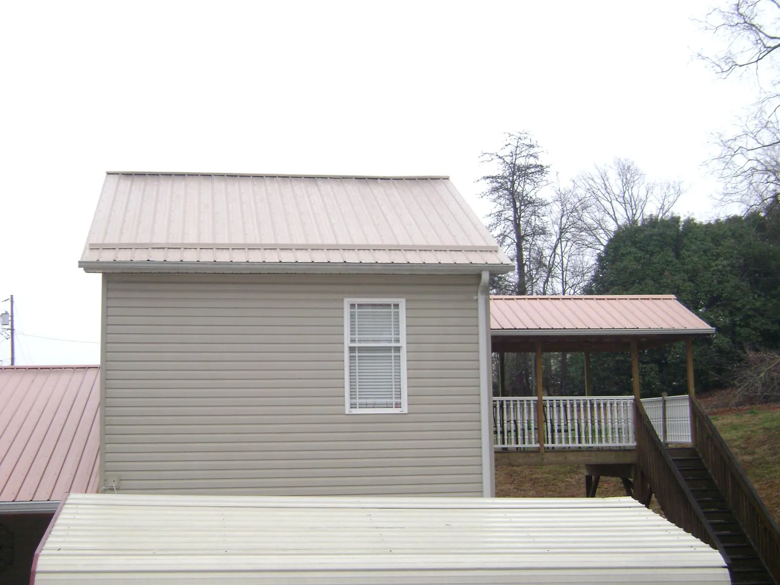 Tan metal roofs on a two story addition and attached porch, from a Roof Replacement job in East Weymouth