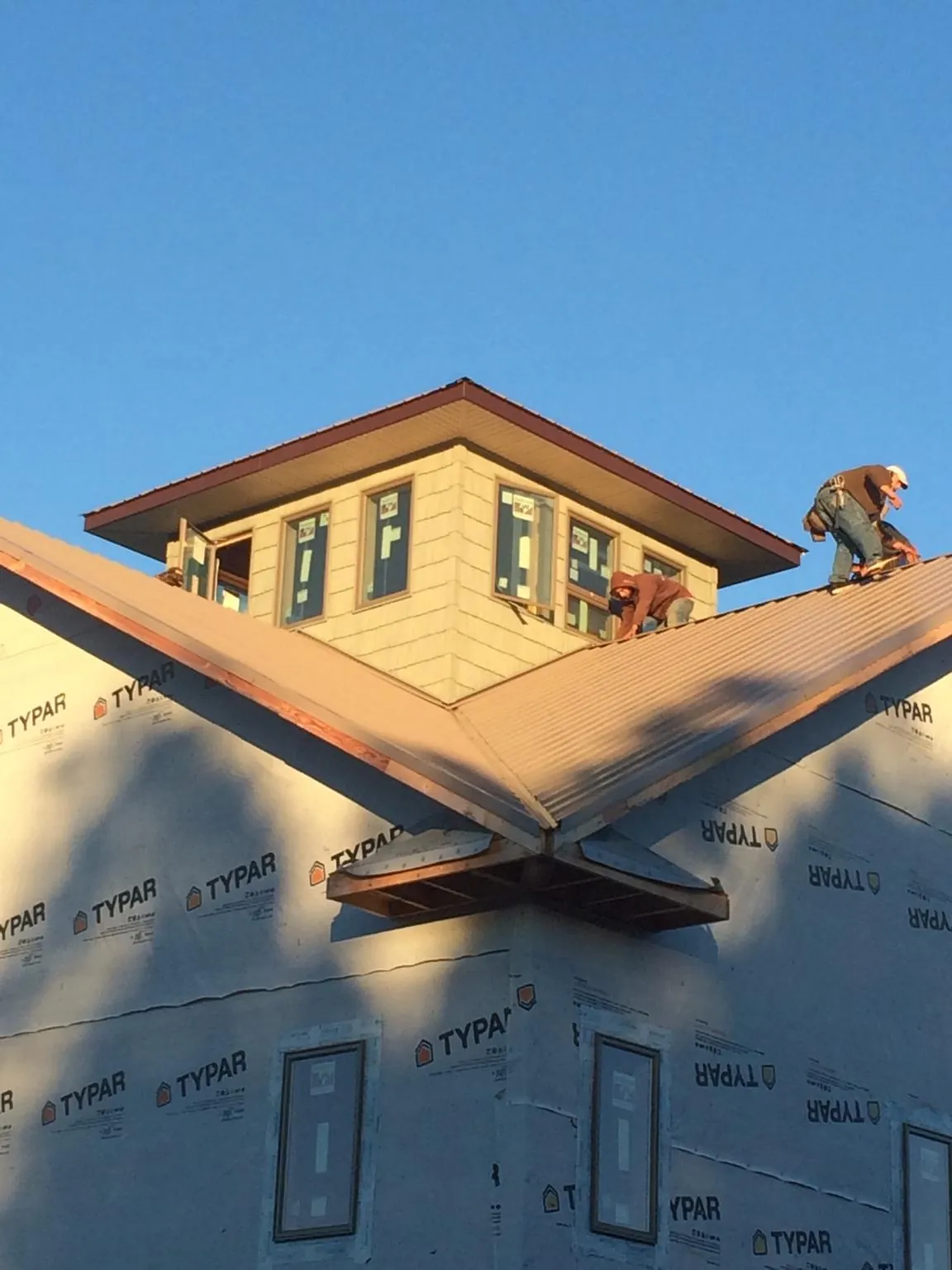 Roofers working around a rooftop cupola on a new metal roof at sunset — Roof Waterproofing in East Weymouth by Roofing Brothers